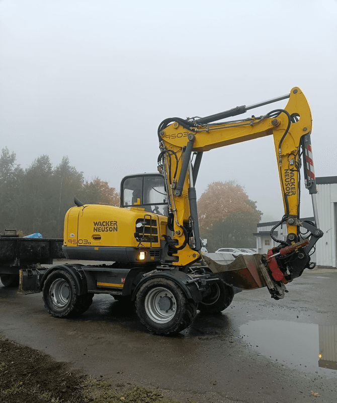 Wacker Neuson-grävmaskin på en grusplan i dimma